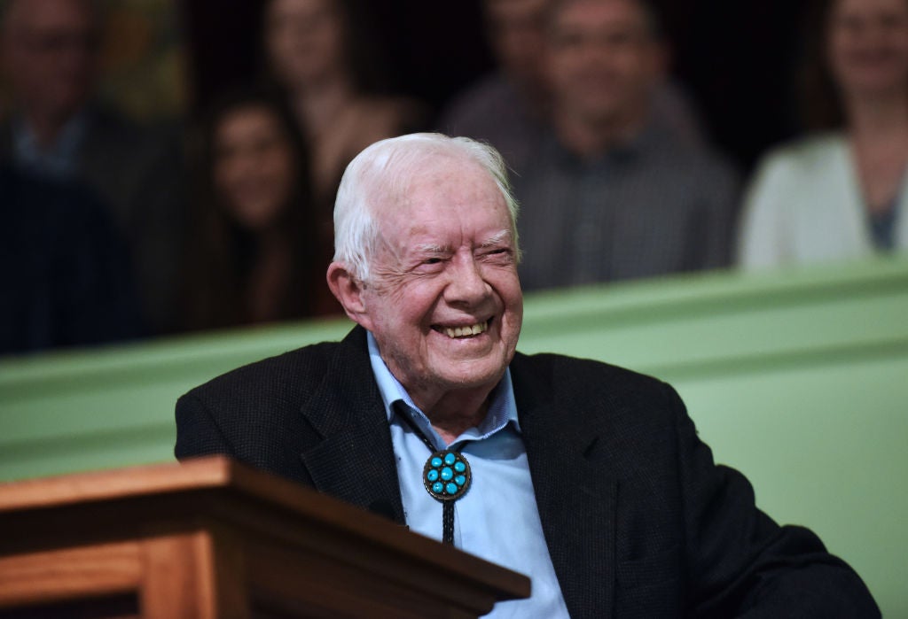 Jimmy Carter smiling sitting at podium