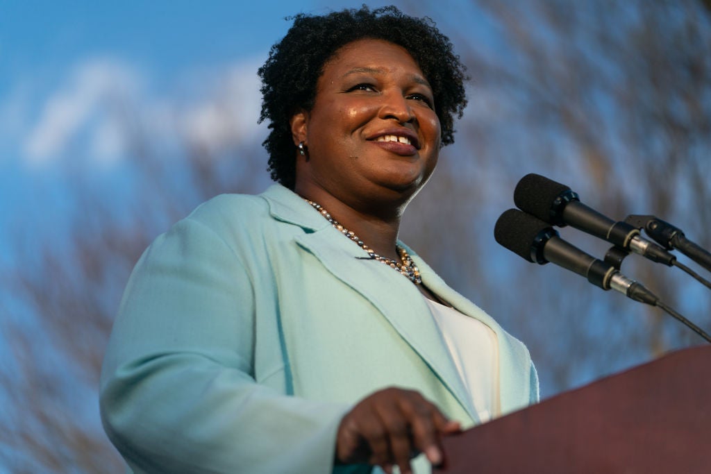 Stacey Abrams at a microphone smiling