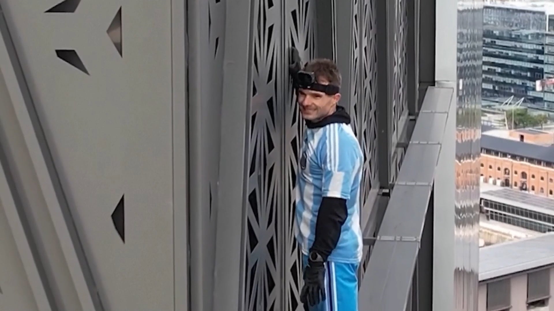 Man in Argentina soccer jersey free-climbing tower