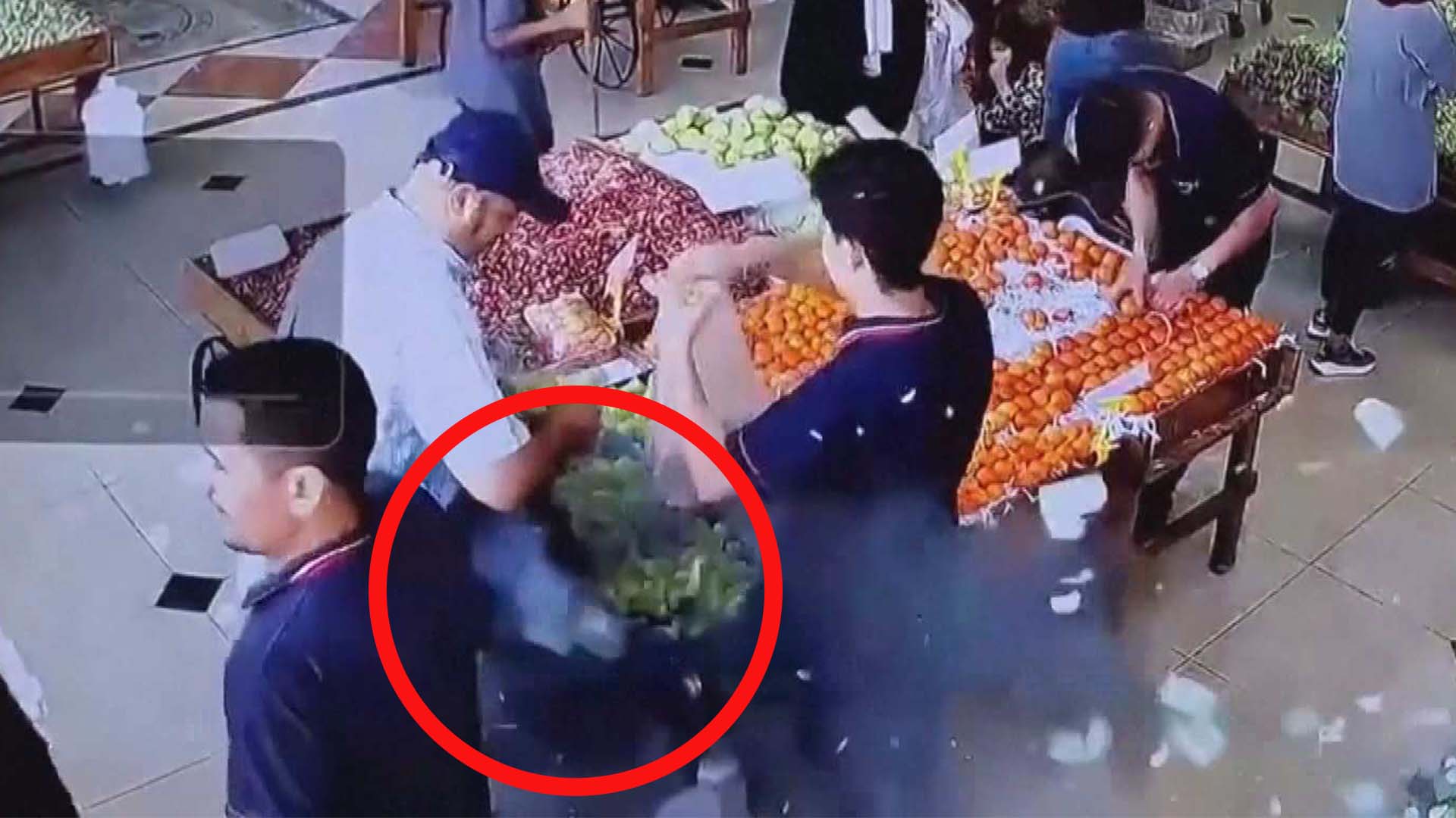 People standing in a fruit market as a man's messenger bag explodes / red circle over the exploding bag