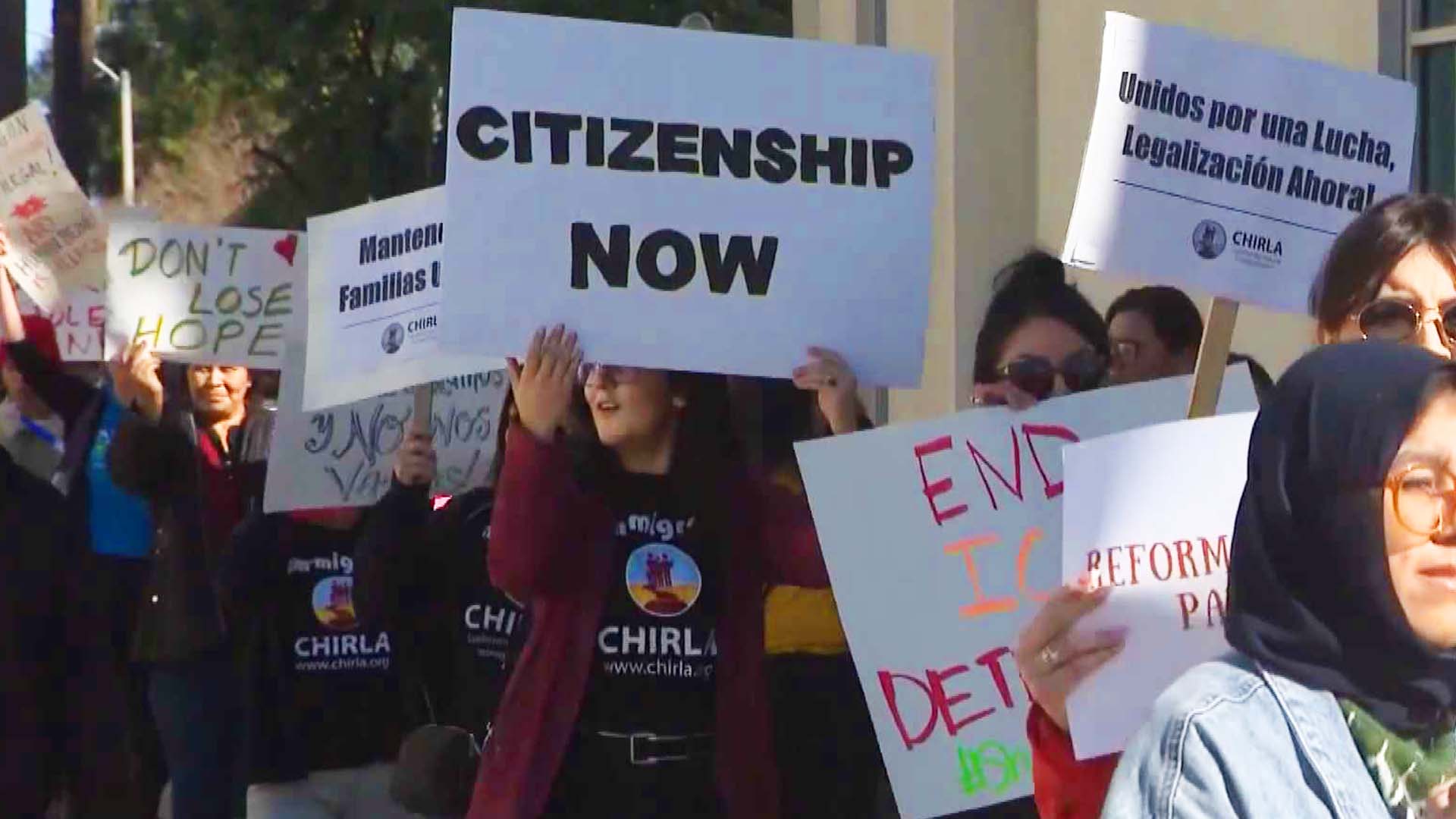 People holding signs at rally for immigrants