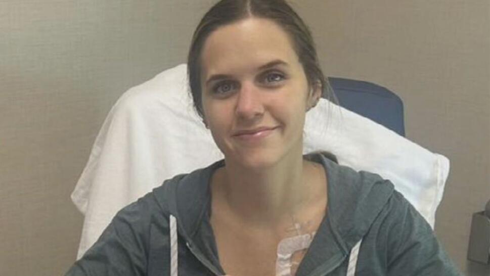 Laura Mock smiling for picture in hospital wearing a grey sweater