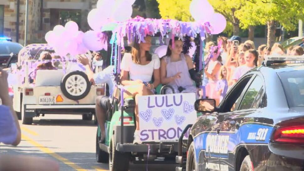 Lulu Gribbin on back of golf cart with purple decorations on it